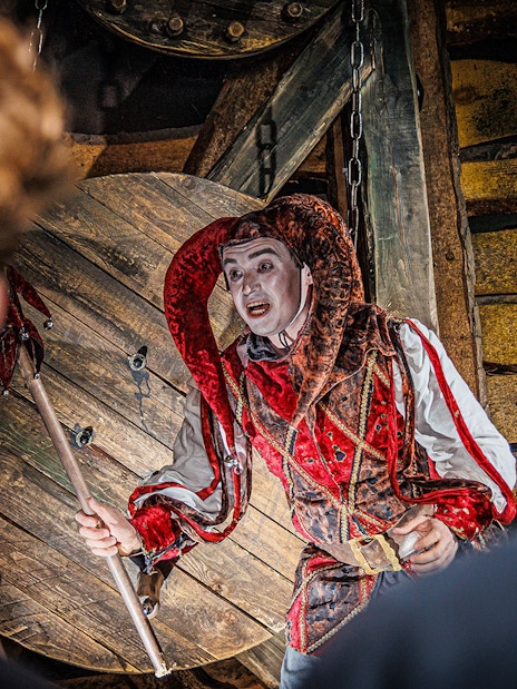 Jester performing at the Berlin Dungeon with audience in foreground.