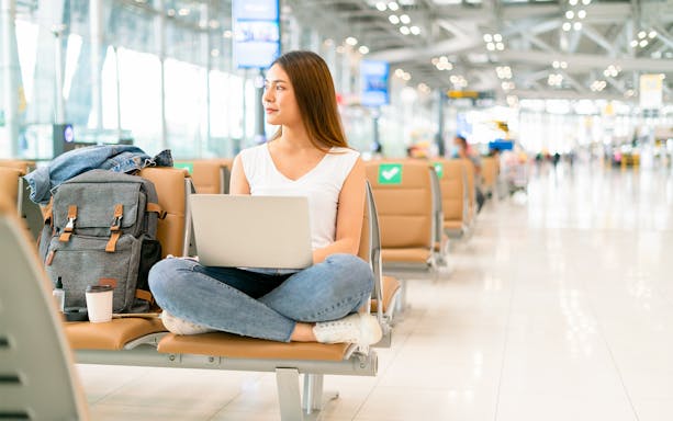 Traveller using a laptop while seated in an airport terminal.