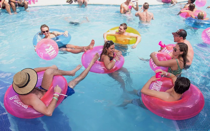 People relaxing on colorful floaties in the pool at Mandala Beachclub Cancun.