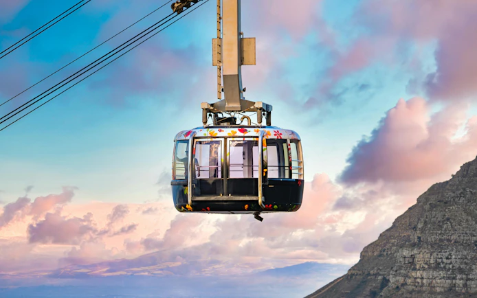 Cable car ascending Table Mountain, Cape Town, with scenic sky and mountain view.