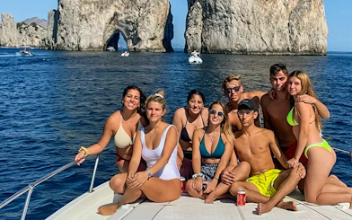 Group enjoying boat tour near Faraglioni rocks, Capri.