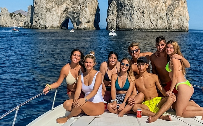 Group enjoying boat tour near Faraglioni rocks, Capri.