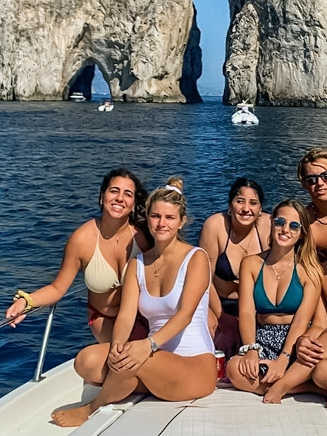Group enjoying boat tour near Faraglioni rocks, Capri.