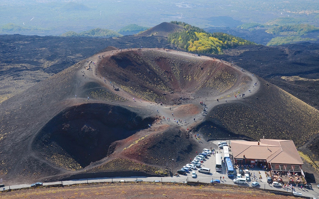 Tourists exploring volcanic craters on Mount Etna in Catania, Sicily.