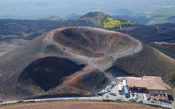 Tourists exploring volcanic craters on Mount Etna in Catania, Sicily.