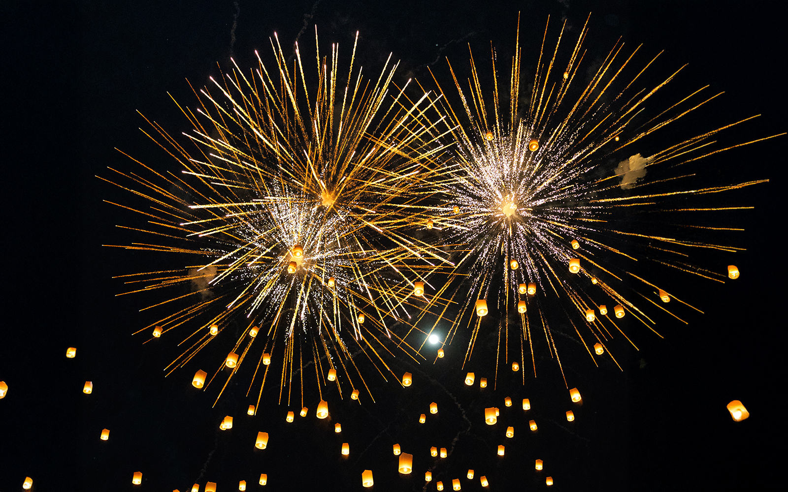 Fireworks and lanterns illuminate the night sky during Yi Peng and Loy Krathong Festival 2025.