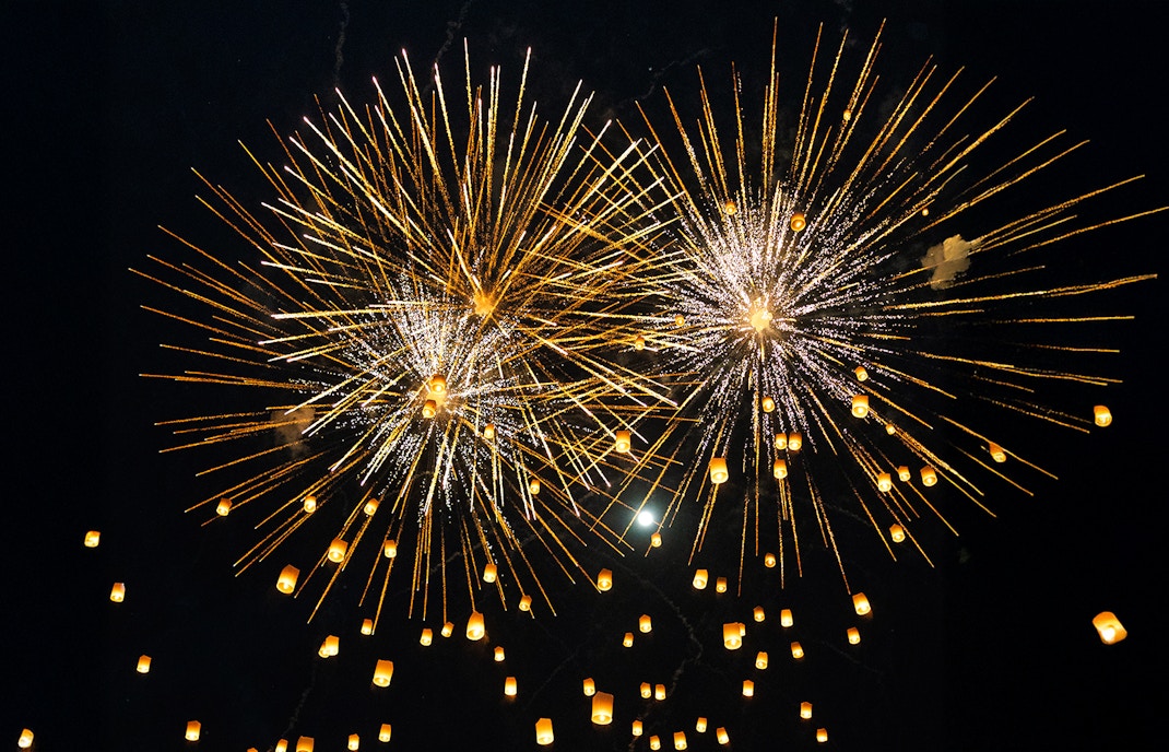 Yi Peng and Loy Krathong Festival 2025, fireworks and floating lanterns illuminate the night sky in Thailand.