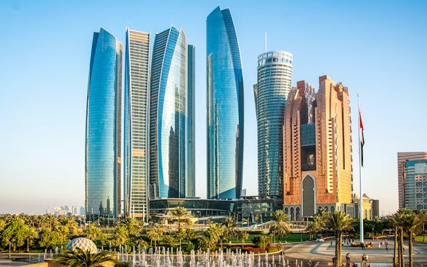 Etihad Towers skyline in Abu Dhabi with surrounding gardens and fountains.