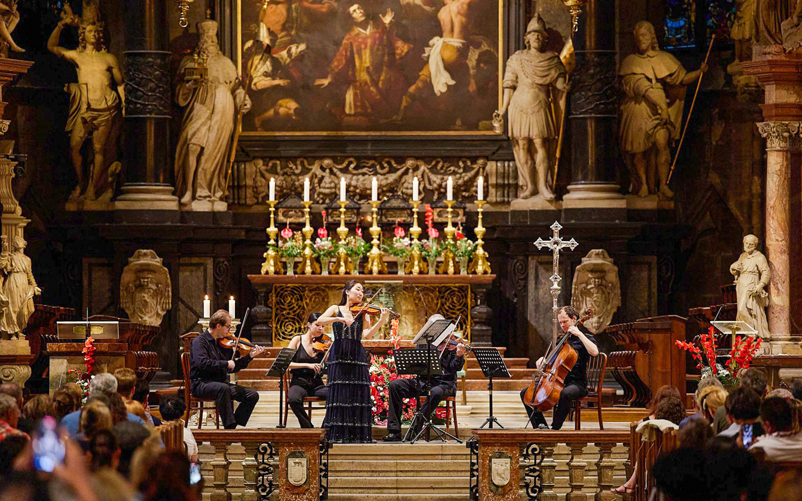 Orchestra performing inside St. Stephen's Cathedral, Vienna, with audience watching.