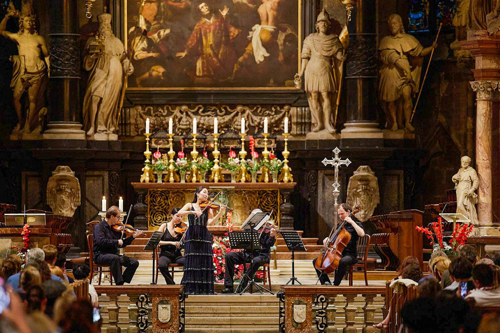 Orchestra performing inside St. Stephen's Cathedral, Vienna, with audience watching.