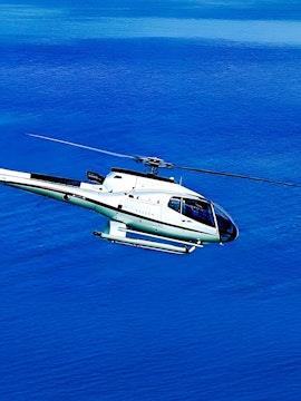 Helicopter flying over blue water in Dubai.