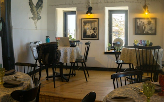 Interior of Pablo Neruda's house with dining tables, chairs, and framed photographs.