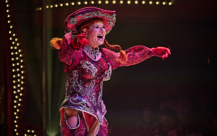 Performer in vibrant costume on stage at Atomic Saloon Show.
