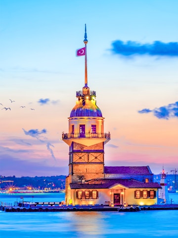Maiden's Tower at sunset in Istanbul, Turkey, with city skyline in the background.