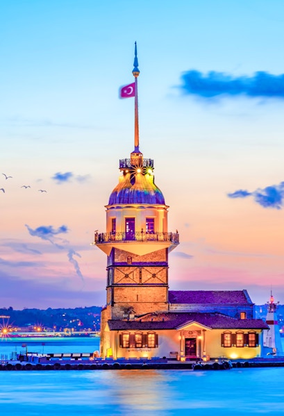 Maiden's Tower at sunset in Istanbul, Turkey, with city skyline in the background.