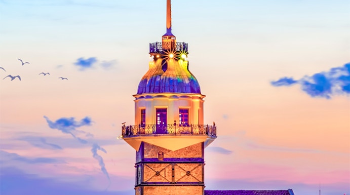 Maiden's Tower at sunset in Istanbul, Turkey, with city skyline in the background.