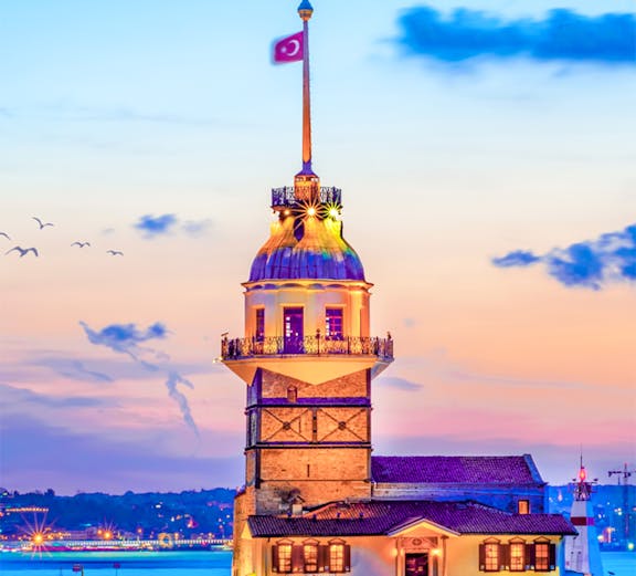 Maiden's Tower at sunset in Istanbul, Turkey, with city skyline in the background.