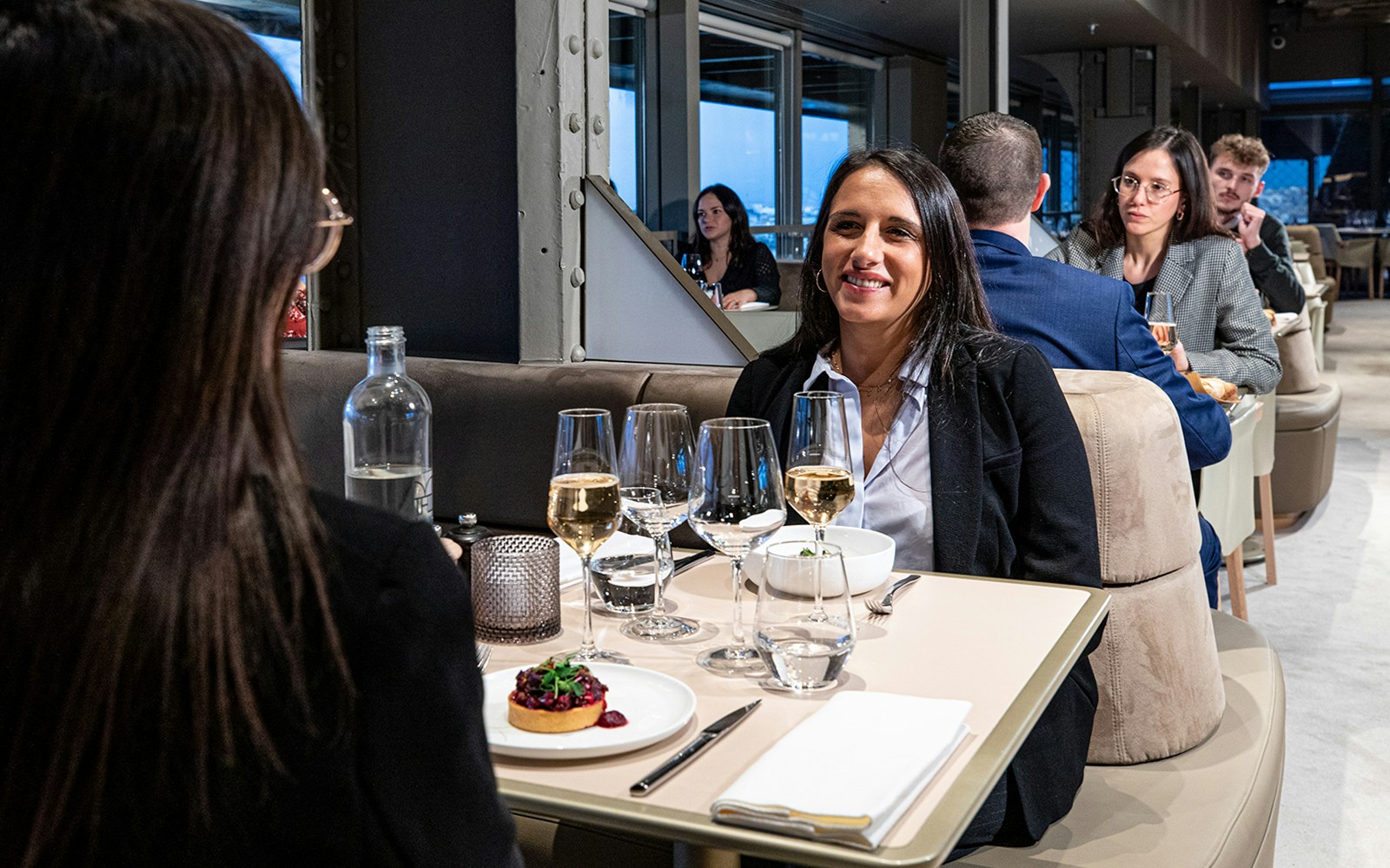 Women dining at Eiffel Tower restaurant with view of Seine River, Paris.