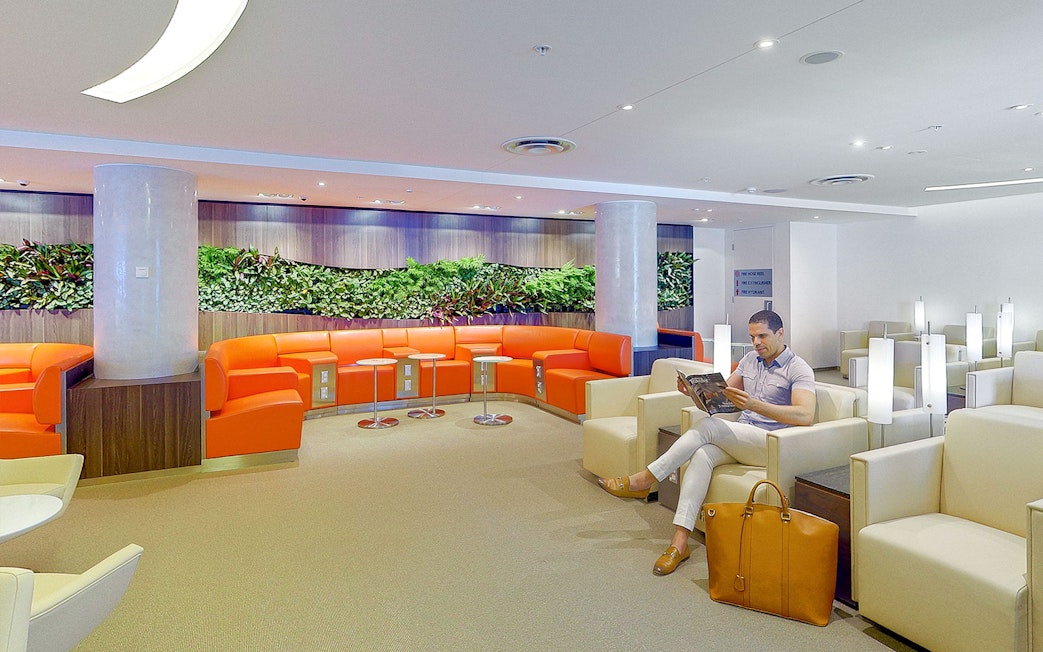 Plaza Premium Lounge seating area with traveler reading, International Departures.