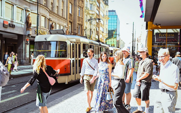 Tourists walking near a tram in Prague's Old Town during a Czech cuisine and beer tour.