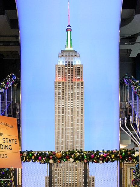 Empire State Building model with Christmas decorations and holiday sign.