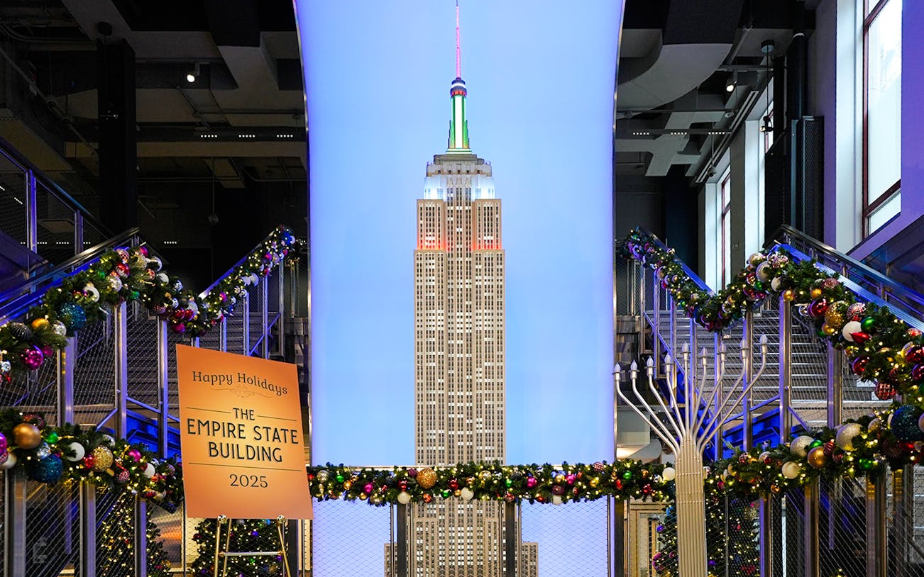 Empire State Building model with Christmas decorations and holiday sign.