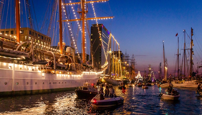 Tall ships illuminated at night during Sail Amsterdam festival.