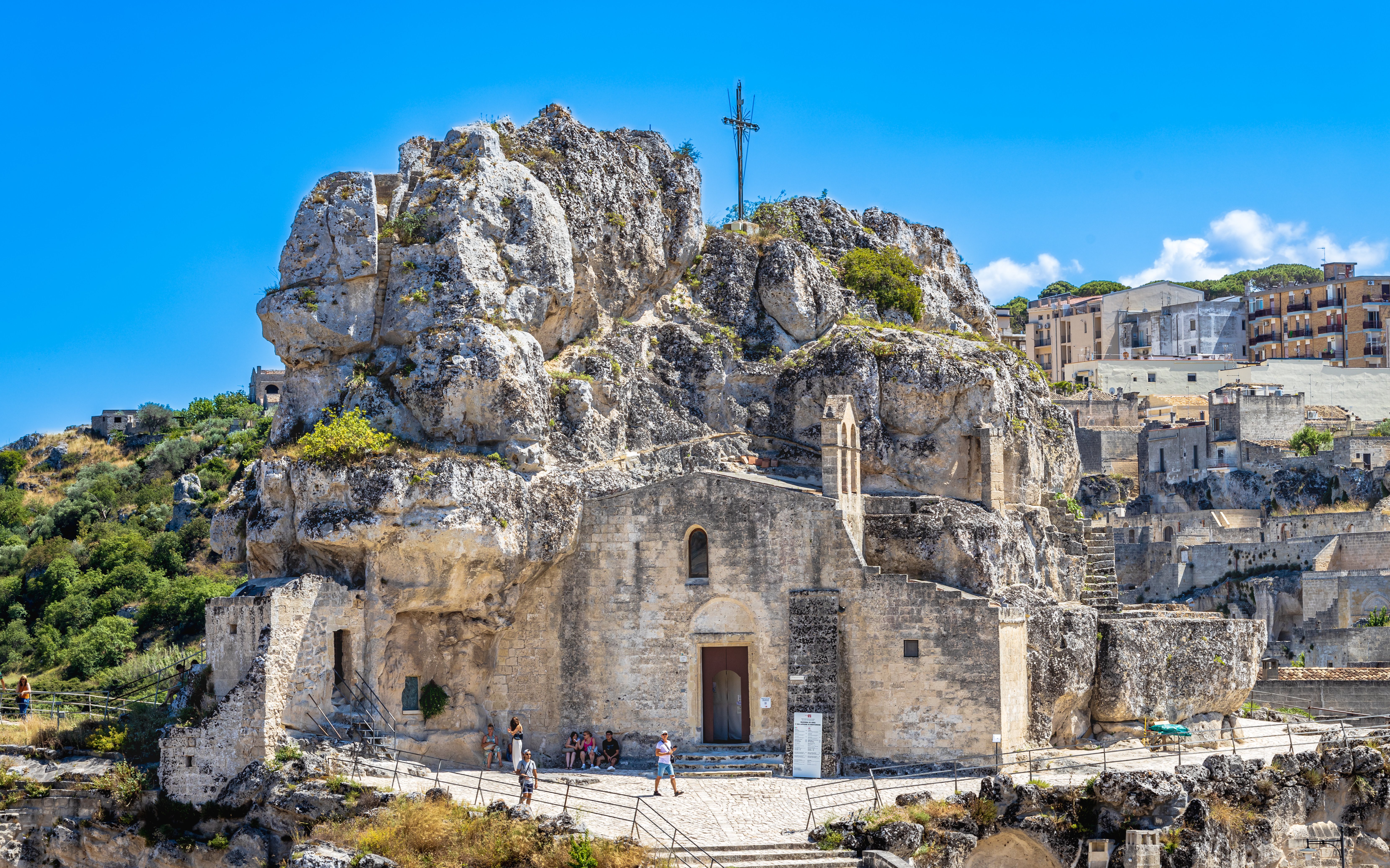 Sasso Caveoso in Matera with ancient rock church and tourists exploring.