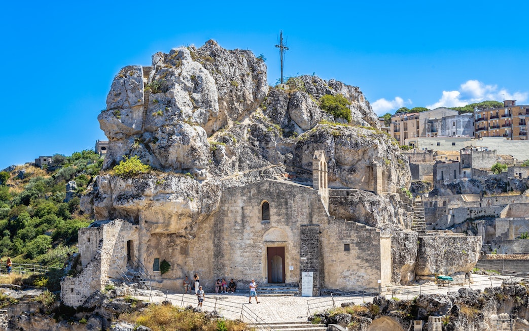Sasso Caveoso in Matera with ancient rock church and tourists exploring.