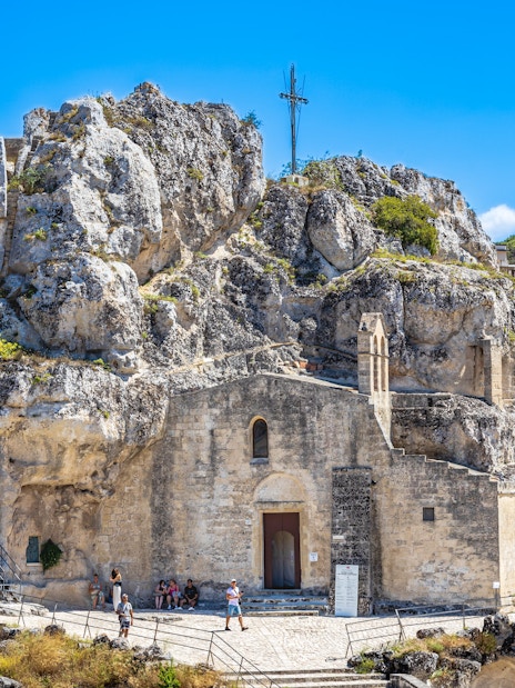 Sasso Caveoso in Matera with ancient rock church and tourists exploring.