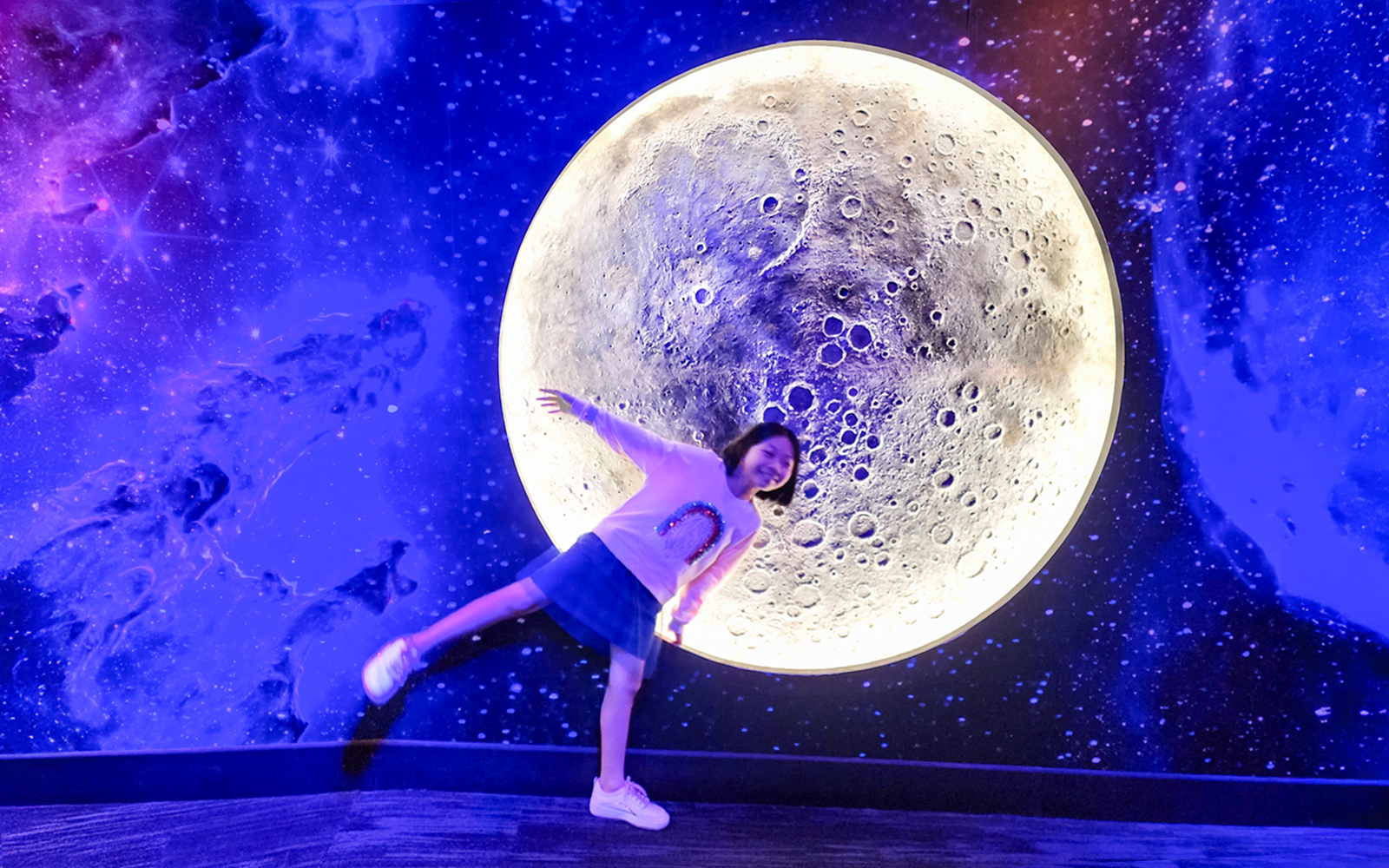 Child posing in front of a moon exhibit at Petrosains, The Discovery Centre, Kuala Lumpur.