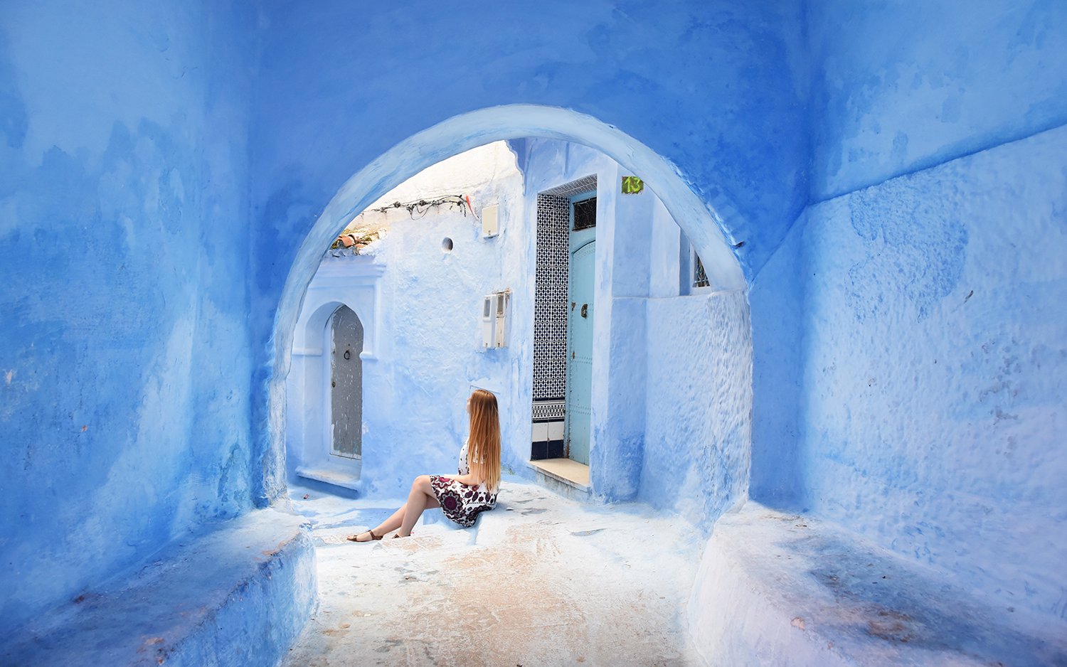 Woman sitting in the blue alleyways of Chefchaouen, Morocco.