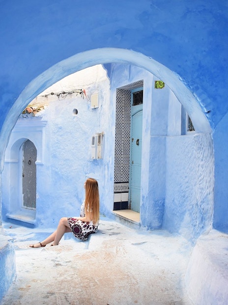 Woman sitting in the blue alleyways of Chefchaouen, Morocco.