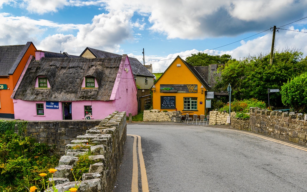Doolin village street with colorful thatched houses and stone walls in Ireland.