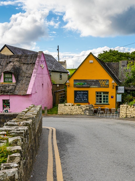 Doolin village street with colorful thatched houses and stone walls in Ireland.