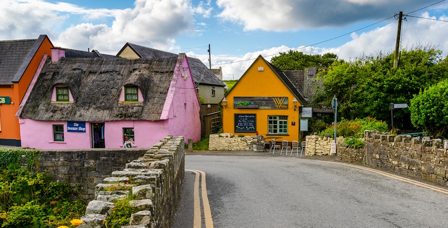 Doolin village street with colorful thatched houses and stone walls in Ireland.