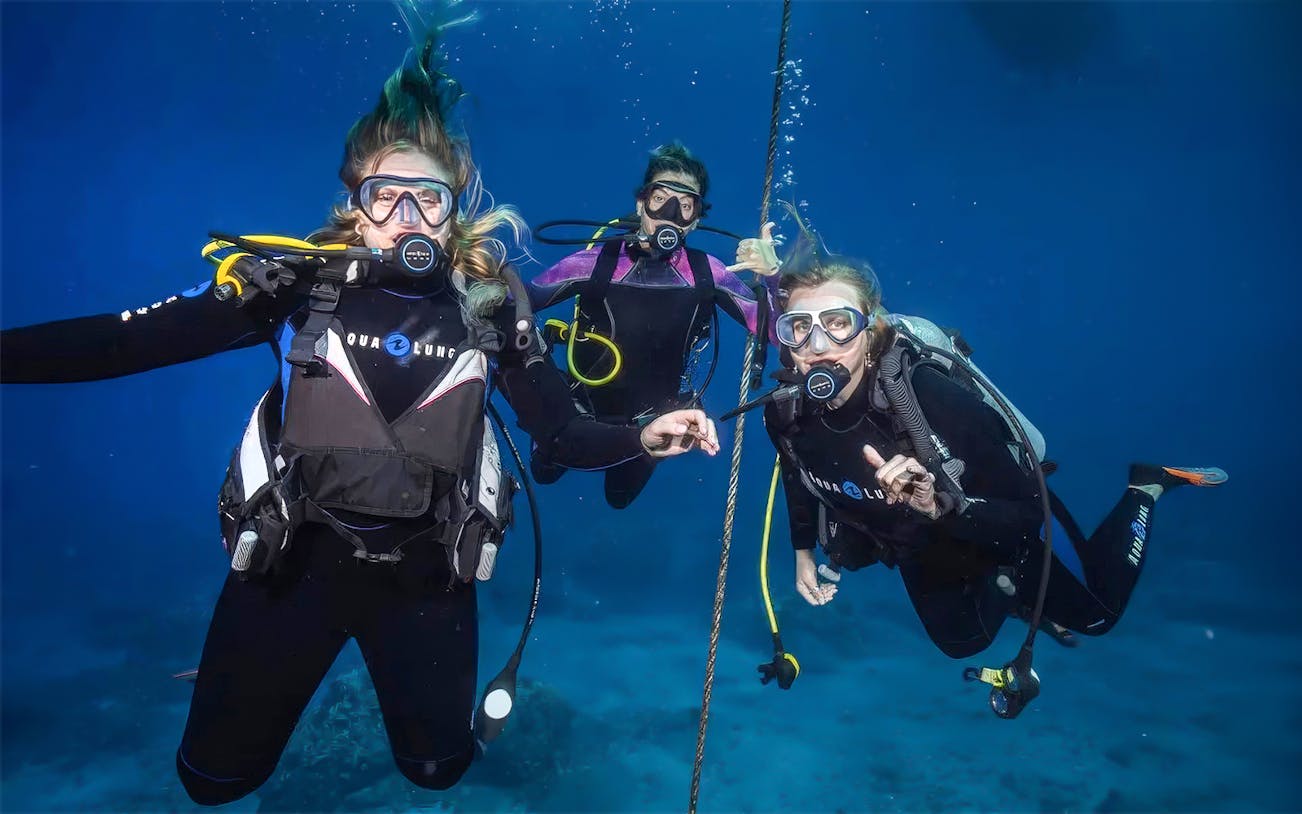 Beginners scuba diving lesson in Maui with three divers underwater.