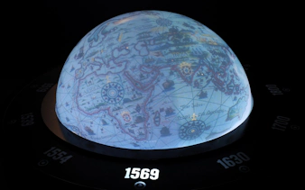 Globe exhibit at World of Discoveries Interactive Digital Exhibition showing historical map from 1569.