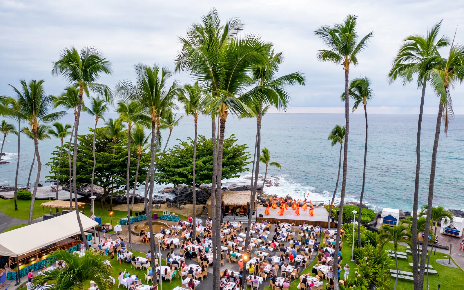 Guests enjoying a luau performance by the ocean at Voyagers of the Pacific Luau venue.