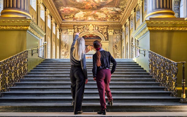 Visitors admiring the ceiling art in the Painted Hall, Old Royal Naval College, London.