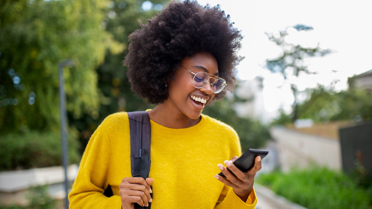 Woman with glasses smiling while checking her phone