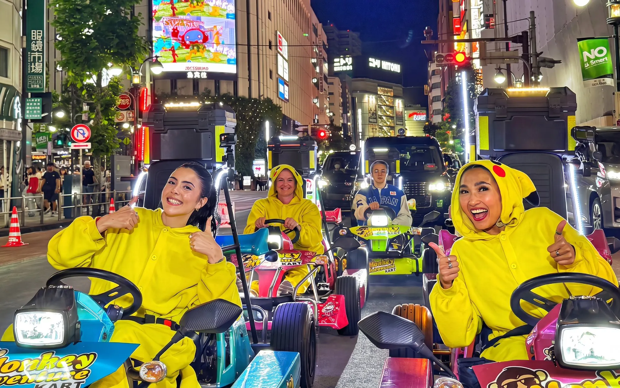 Go-kart riders in costume driving through Shibuya at night.