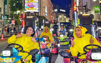 Go-kart riders in costume driving through Shibuya at night.