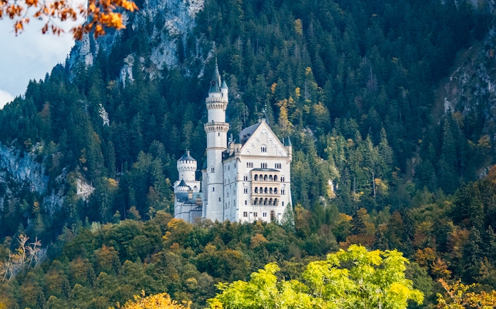 Neuschwanstein Castle surrounded by forested hills, part of the Skip The Line tour from Munich.