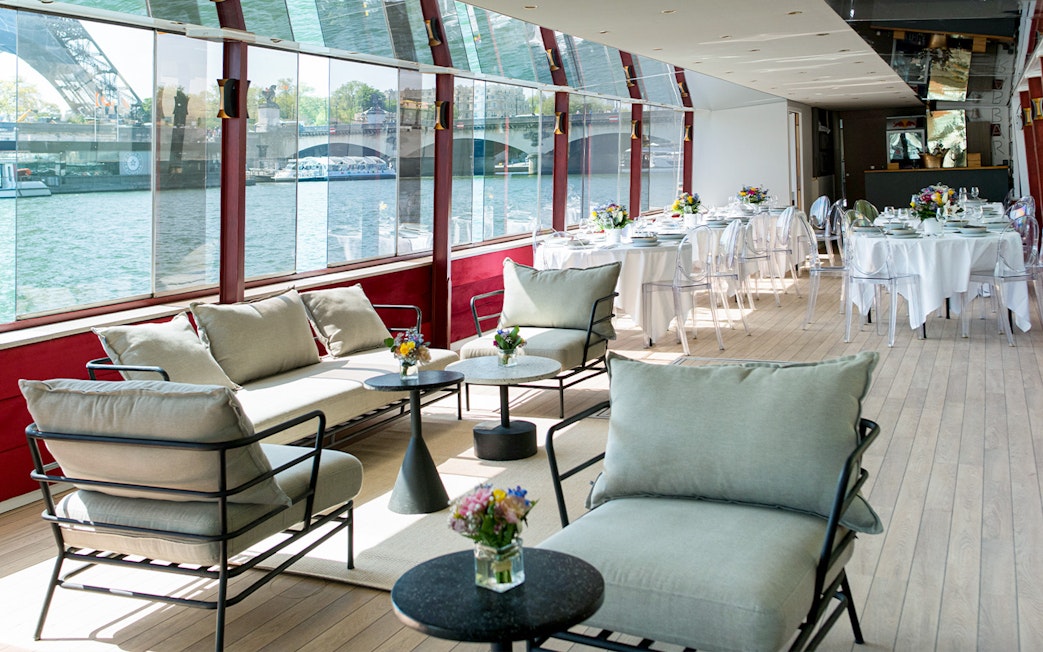 Rooftop seating area on a Parisian boat cruise with tables set for brunch.