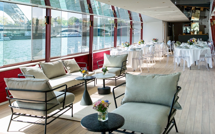 Rooftop seating area on a Parisian boat cruise with tables set for brunch.