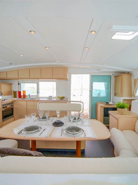 Interior of Santorini sailing catamaran with dining table and sea view.