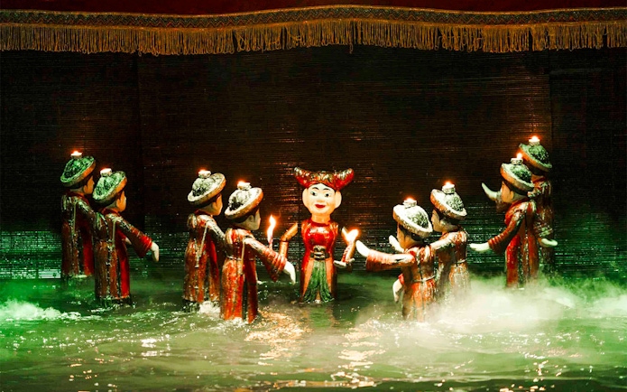 Water puppets holding candles on a misty stage at Thang Long Water Puppet Theatre.