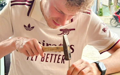 Man crafting jewelry with a hammer in Hoi An workshop.