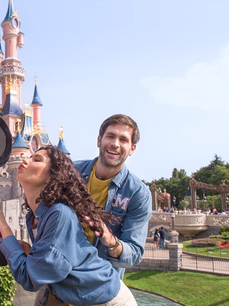 Guests posing with Minnie Mouse at Disneyland Paris with Sleeping Beauty Castle in the background.